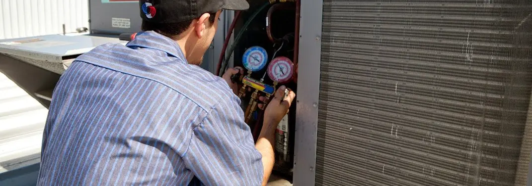 HVAC technician servicing a condenser unit in Huntington Woods